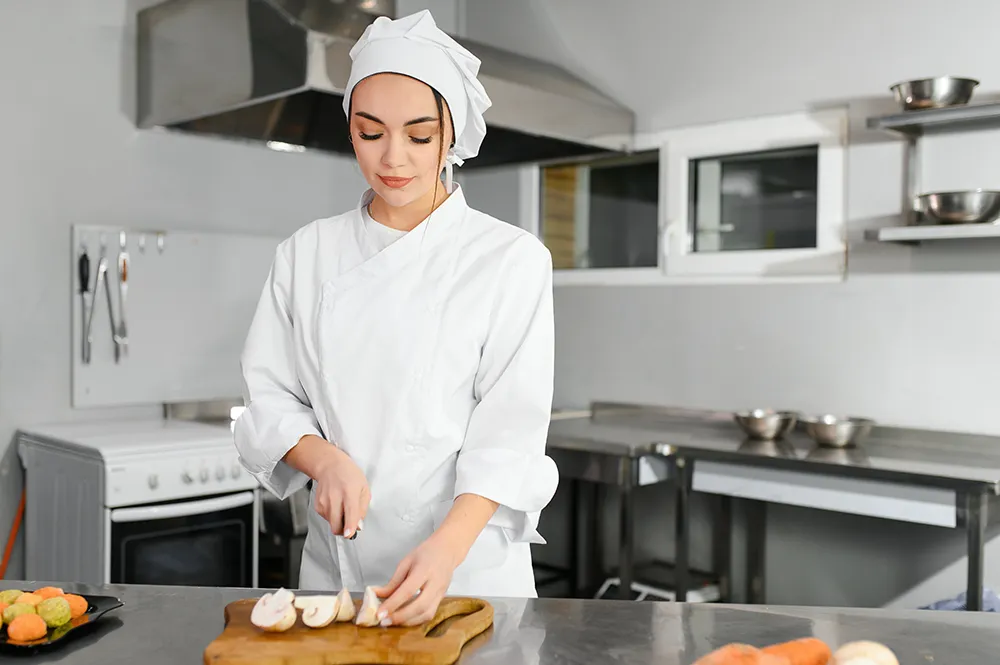 Female culinary student chopping mushrooms