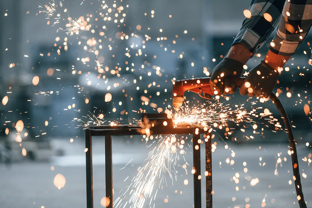 Welder working on metal with sparks flying 